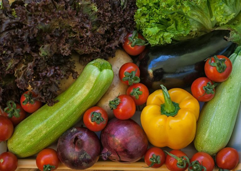 an assortment of harvested vegetables laid out on a wooden table